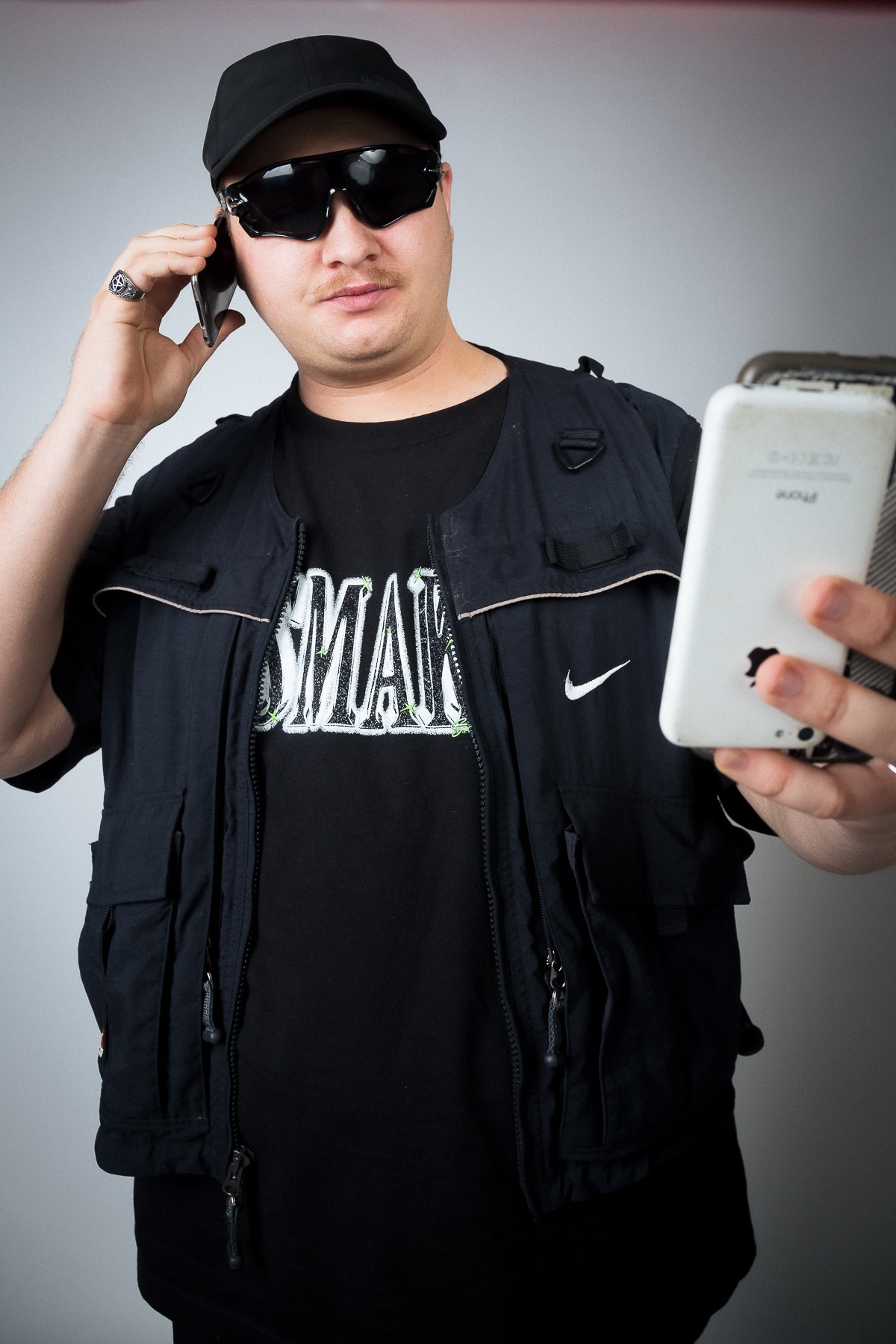 A man holds a phone while modelling Smak (Rapper) merch